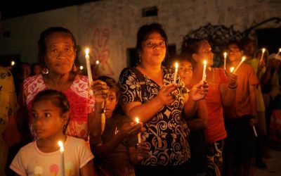 Grupo de mujeres y niñas participan en una vigilia comunitaria a la luz de las velas, simbolizando su compromiso con la defensa del medioambiente y la justicia climática.