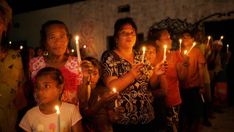 Grupo de mujeres y niñas participan en una vigilia comunitaria a la luz de las velas, simbolizando su compromiso con la defensa del medioambiente y la justicia climática.