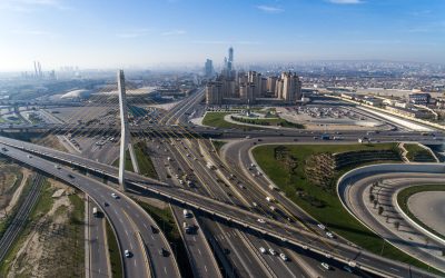 Vista aérea de autopista urbana con puente atirantado y gran circulación vehicular rodeada de edificios modernos.