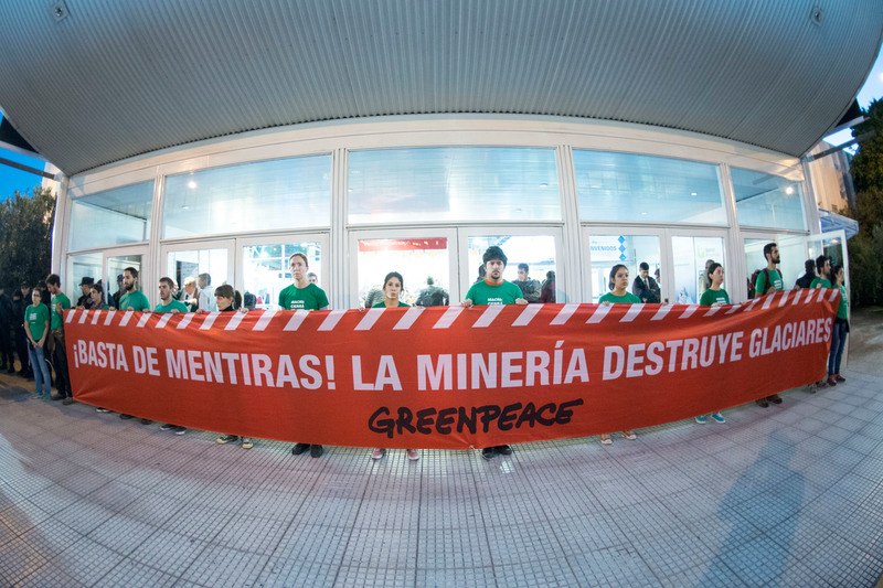Activistas de Greenpeace sosteniendo una pancarta roja que denuncia la destrucción de glaciares por la minería.