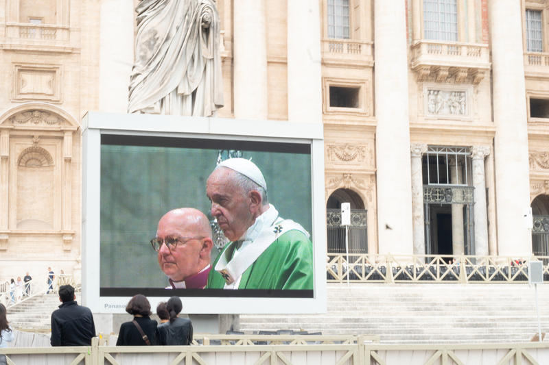 Pantalla gigante muestra al Papa y a un obispo durante una ceremonia en la Plaza de San Pedro