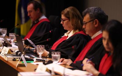 Grupo de jueces con togas negras y detalles rojos participando en una sesión judicial en Brasil.