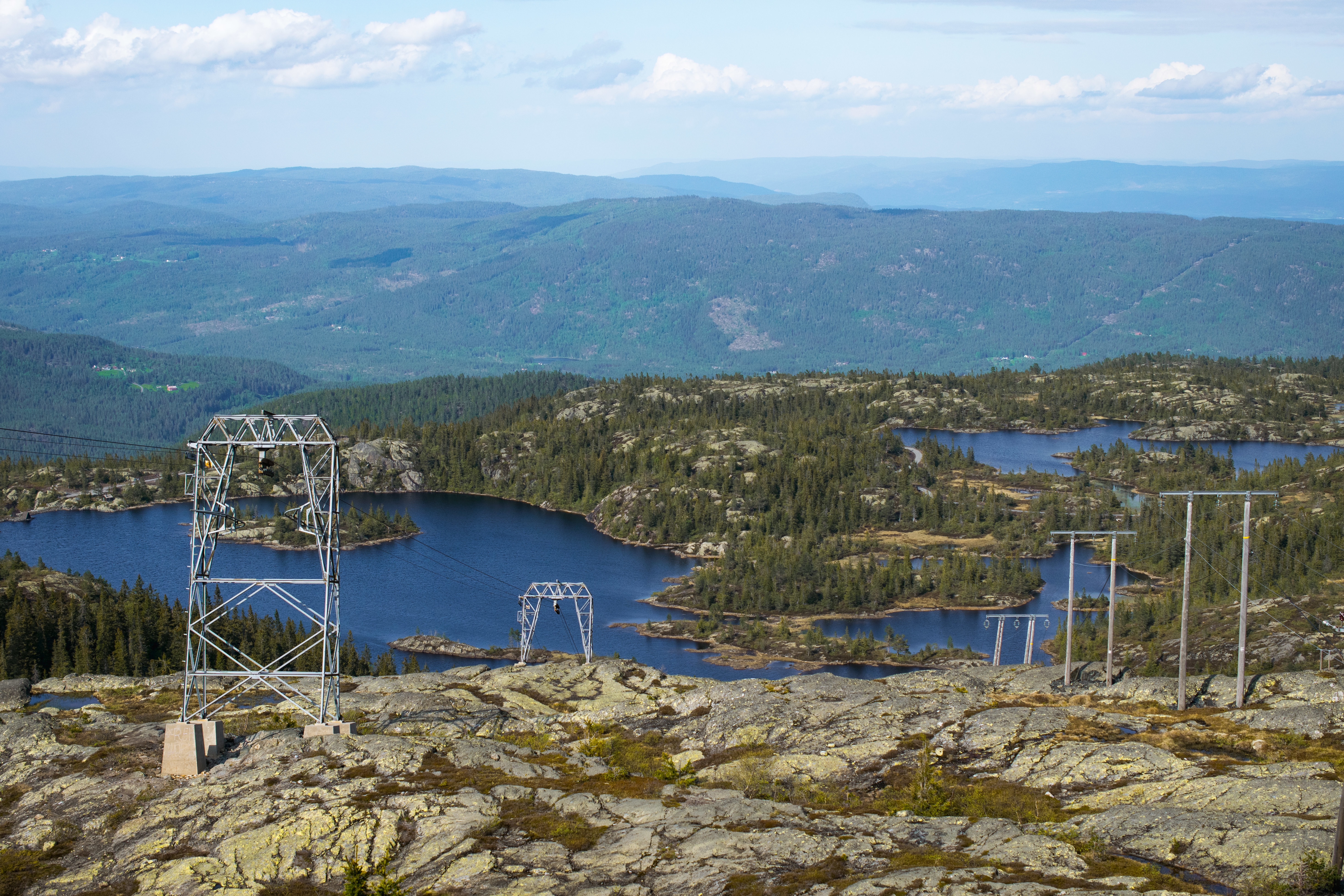 Torres de energía en medio de montañas y lagos azules rodeados de bosques