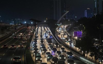 Vista aérea de una autopista urbana congestionada de noche con luces de automóviles formando largas filas en ambos sentidos.