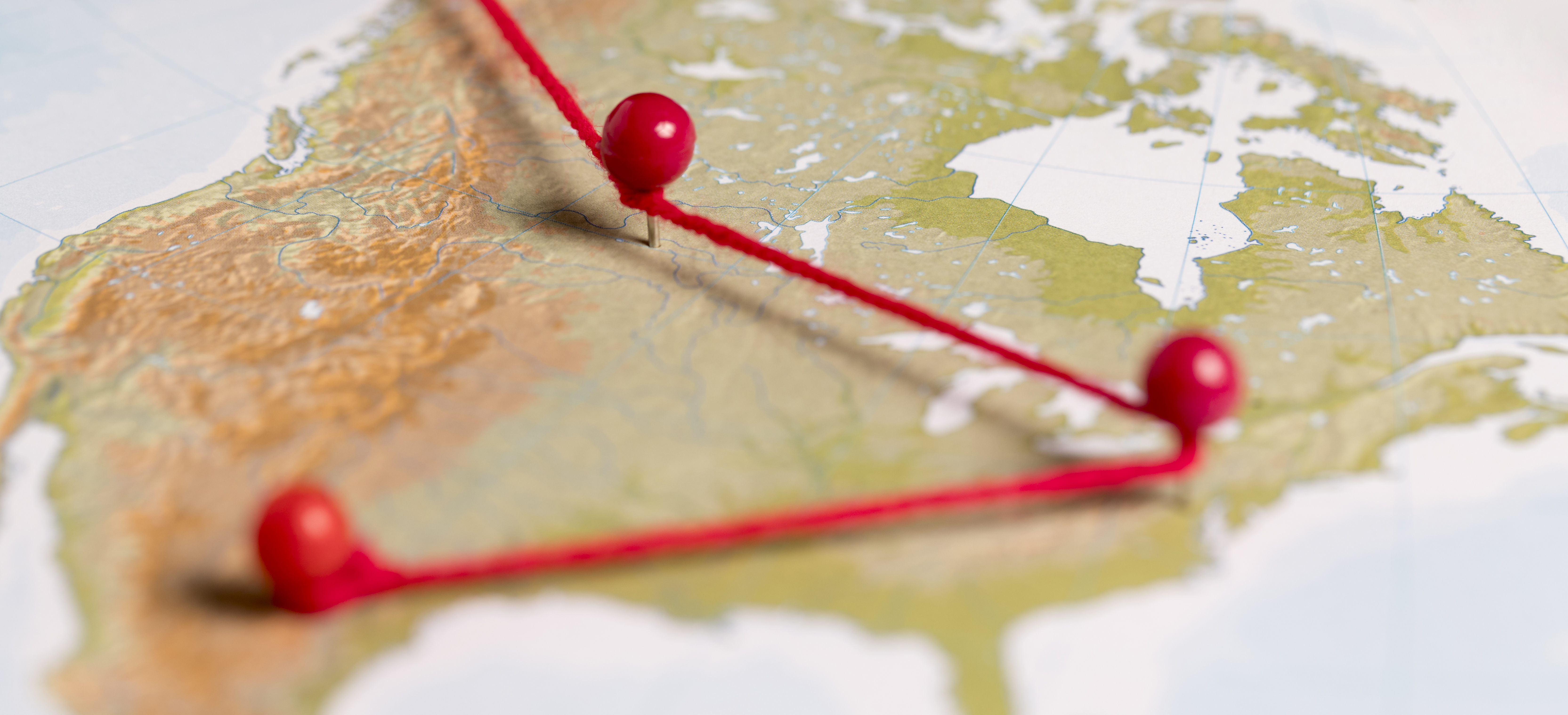 Mapa con alfileres rojos conectados por un hilo, simbolizando rutas o conexiones estratégicas entre diferentes puntos geográficos.