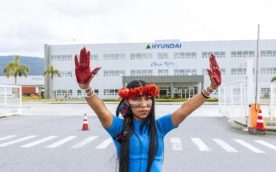 Mujer indígena brasileña con las manos pintadas de rojo protesta frente a una fábrica de Hyundai