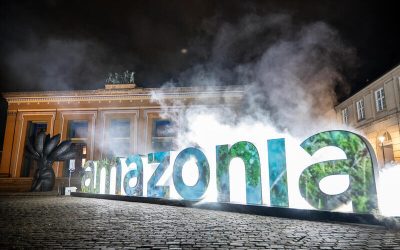 Instalación artística con la palabra “Amazonia” iluminada frente a un edificio histórico